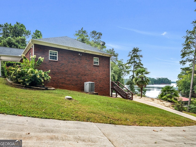 view of side of home with central air condition unit, a water view, and a lawn