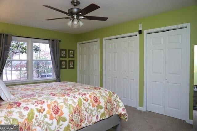 carpeted bedroom with ceiling fan and multiple closets