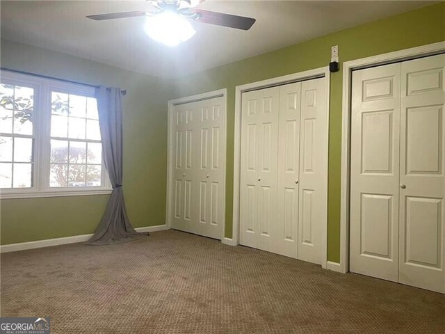 unfurnished bedroom with ceiling fan, carpet floors, and two closets