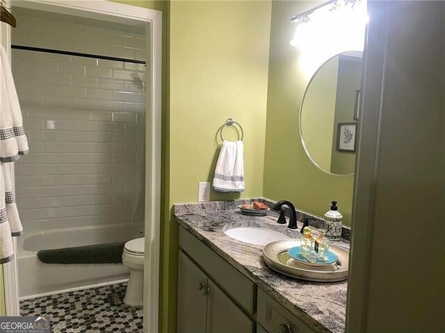 full bathroom with tiled shower / bath, vanity, and toilet