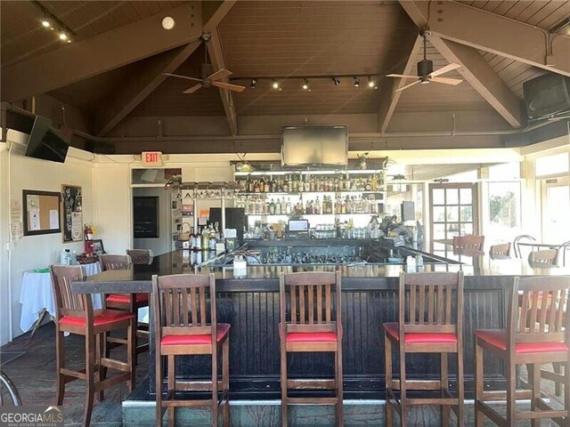 exterior space featuring vaulted ceiling with beams, rail lighting, ceiling fan, and wooden ceiling