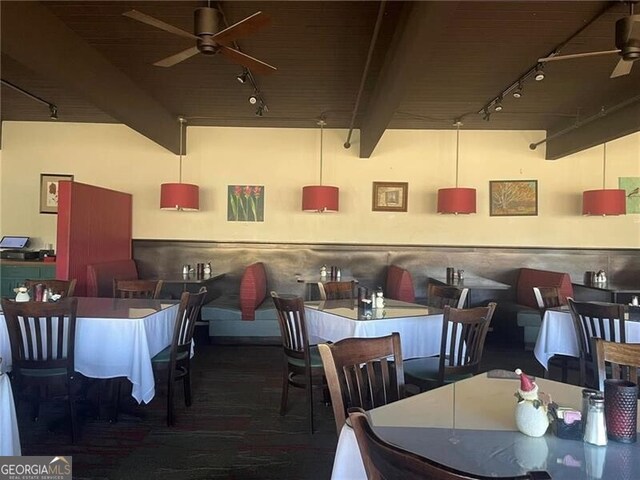 dining room featuring beamed ceiling, rail lighting, ceiling fan, and wood ceiling