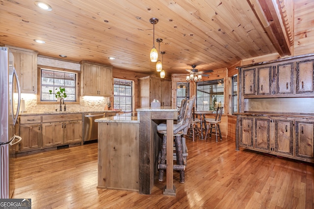 kitchen featuring appliances with stainless steel finishes, light wood-style floors, a sink, a center island, and wooden ceiling