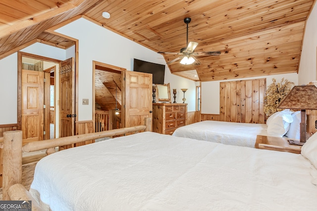 bedroom with lofted ceiling, wood ceiling, wooden walls, wainscoting, and ceiling fan