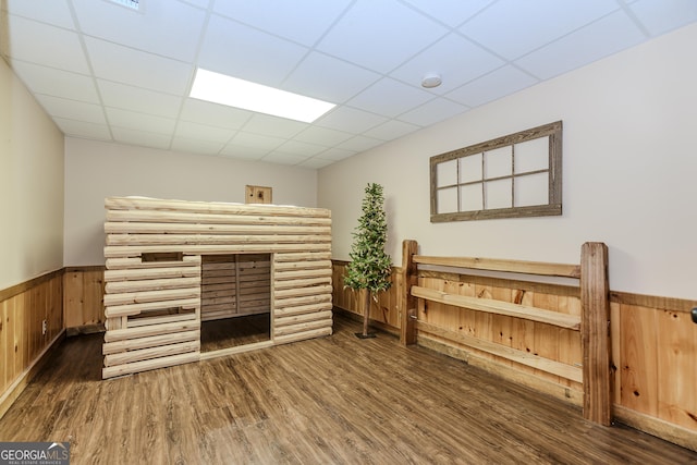 living room featuring wood finished floors, wainscoting, a paneled ceiling, and wooden walls