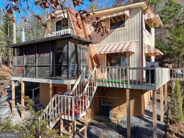 back of house with central AC unit, a sunroom, and stairway