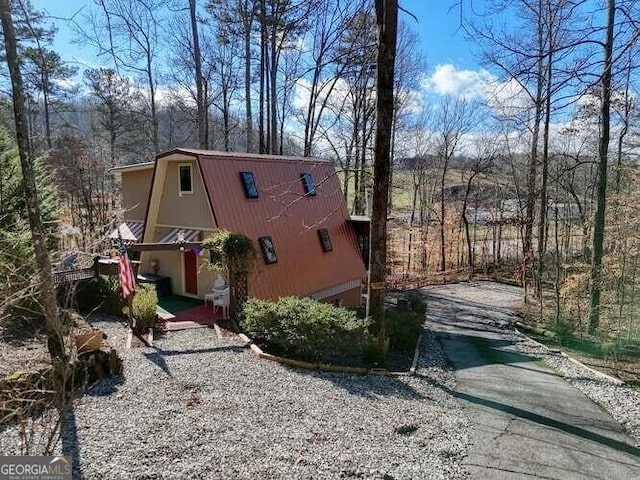 view of home's exterior with driveway and a gambrel roof