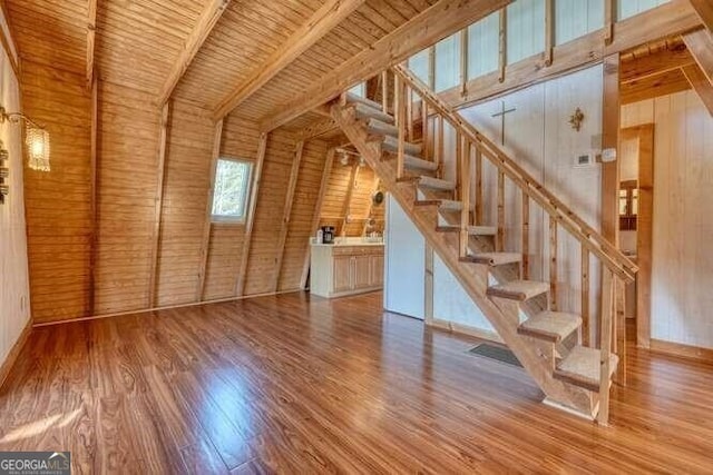 unfurnished living room with wood walls, stairs, and wood finished floors