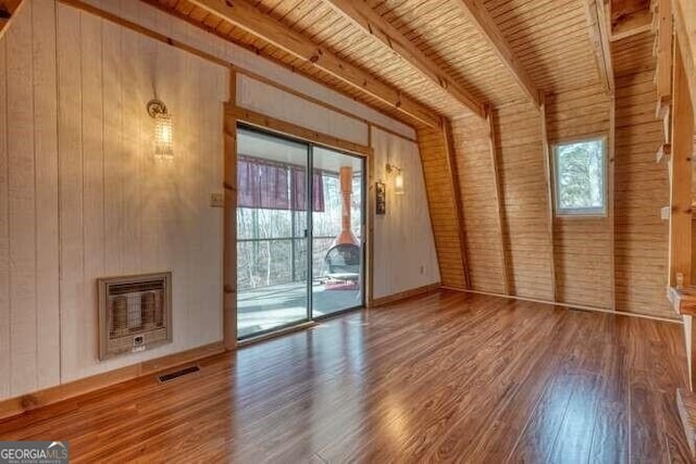 unfurnished living room featuring visible vents, plenty of natural light, heating unit, and wood finished floors