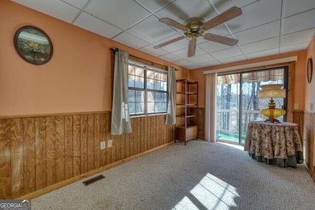 spare room with a wainscoted wall, visible vents, a drop ceiling, and wood walls