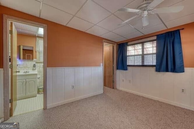 empty room with a paneled ceiling, a wainscoted wall, and carpet