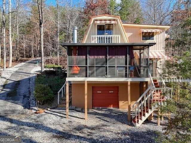 view of front of house featuring stairs, driveway, a sunroom, and a garage