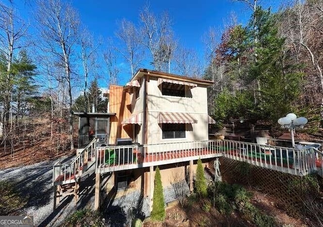 rear view of house with a wooden deck and stucco siding