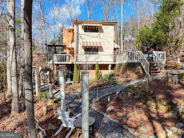 back of property featuring stairway, a deck, and stucco siding