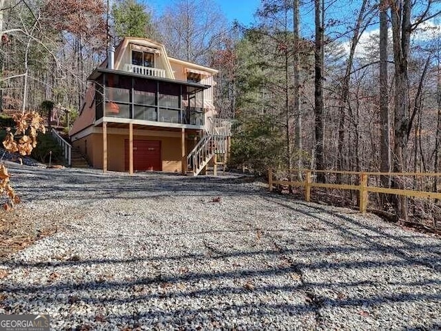 exterior space with gravel driveway, a sunroom, and stairs