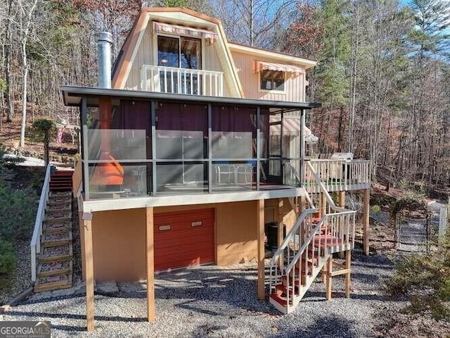 view of front facade with a garage, driveway, stairway, and a sunroom