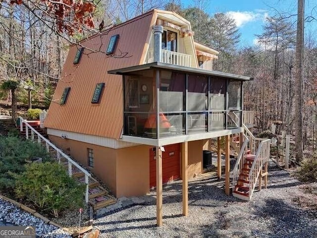 view of side of home featuring central AC unit, stairway, and a sunroom