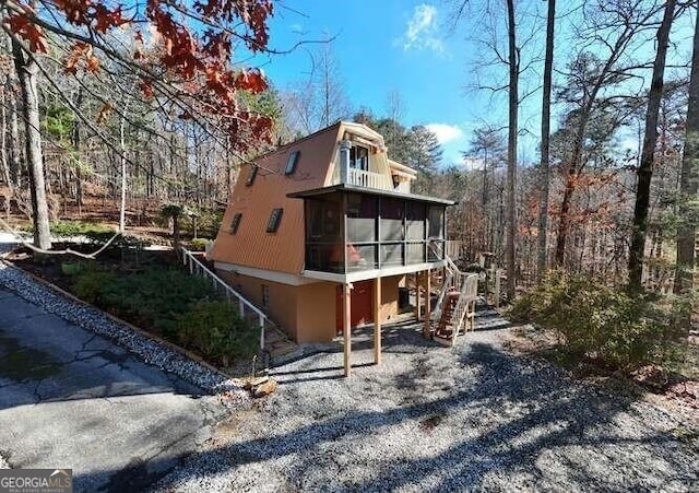 view of side of property with a sunroom and stairway