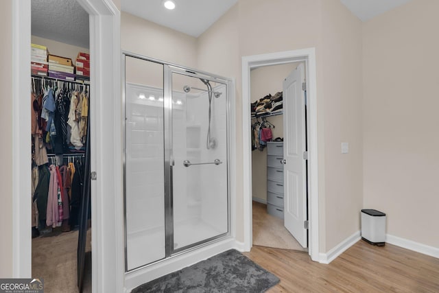 bathroom with wood-type flooring, a textured ceiling, and a shower with shower door