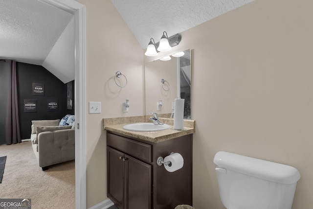 bathroom with toilet, vanity, a textured ceiling, and vaulted ceiling