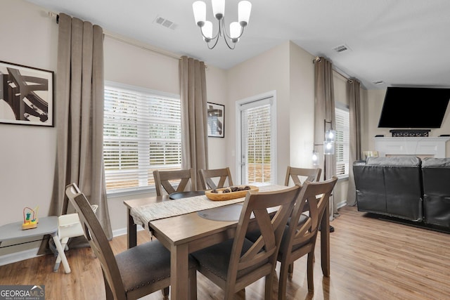 dining space with light hardwood / wood-style flooring, an inviting chandelier, and a healthy amount of sunlight