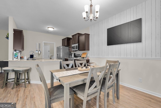 dining space with light hardwood / wood-style flooring and a notable chandelier