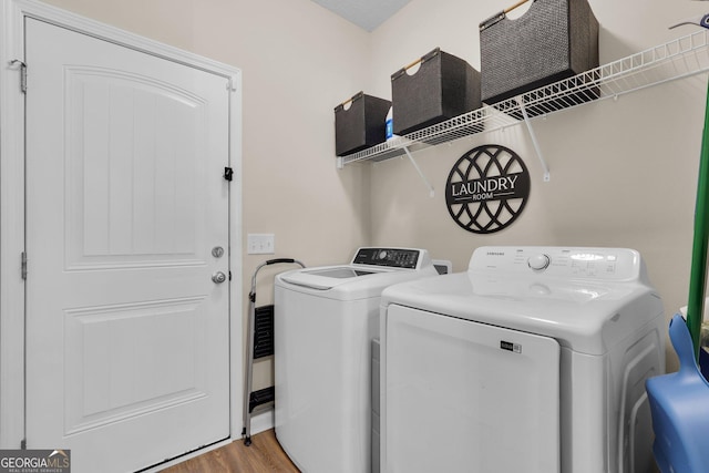 laundry room with wood-type flooring and separate washer and dryer