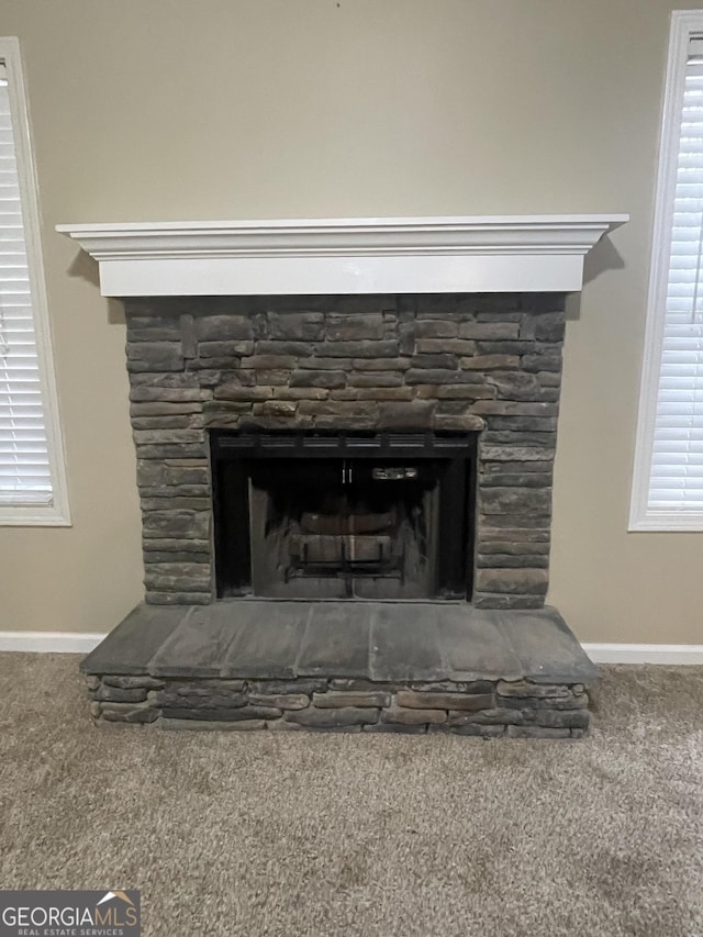 room details featuring a stone fireplace and carpet