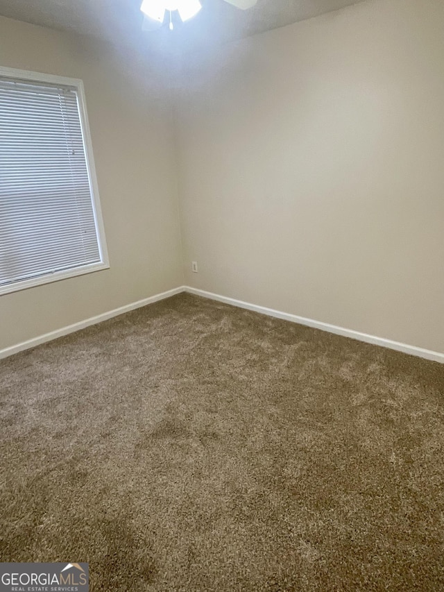 carpeted spare room featuring ceiling fan