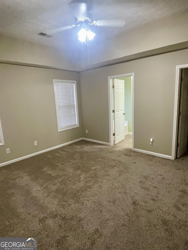 carpeted empty room featuring ceiling fan and a textured ceiling