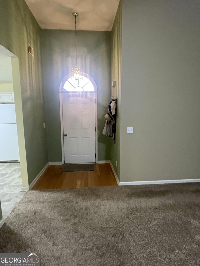 carpeted entryway with a notable chandelier