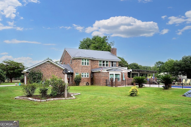 view of front of property featuring brick siding, fence, a front yard, metal roof, and a chimney