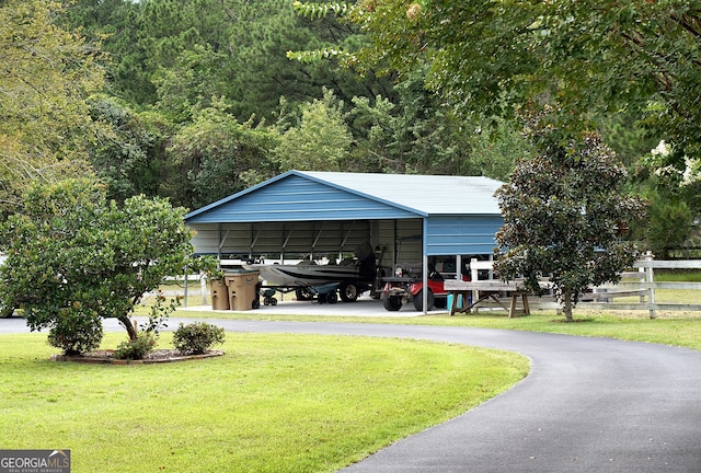 view of car parking with a detached carport, driveway, and fence