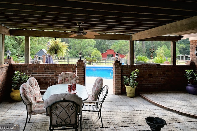 view of patio / terrace with an outdoor pool, outdoor dining area, ceiling fan, and fence