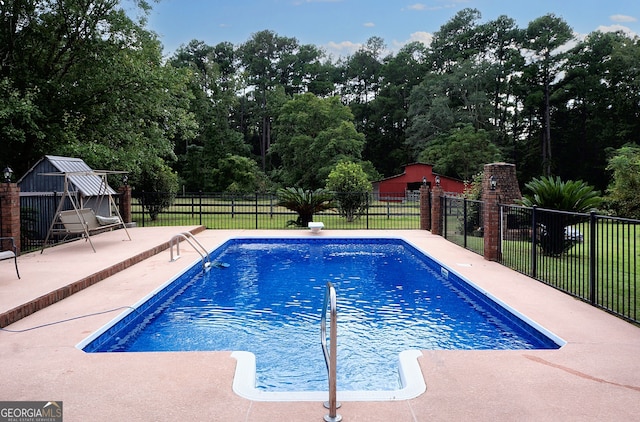 view of swimming pool with a patio area, fence, a fenced in pool, and an outdoor structure