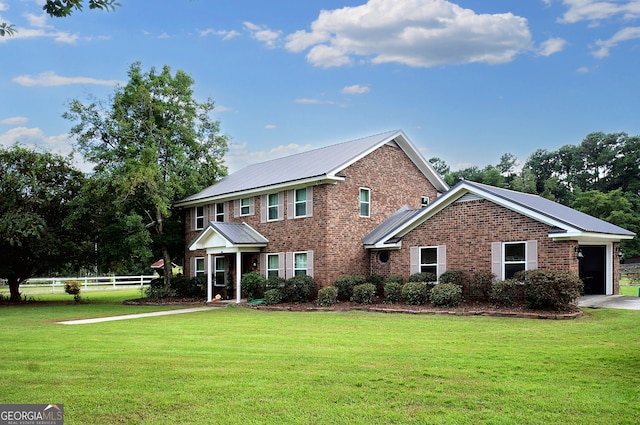 colonial house with driveway, brick siding, a front lawn, and fence