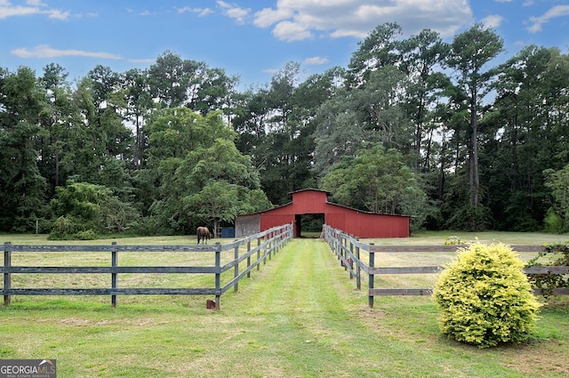 view of gate featuring a rural view, an outdoor structure, and a lawn