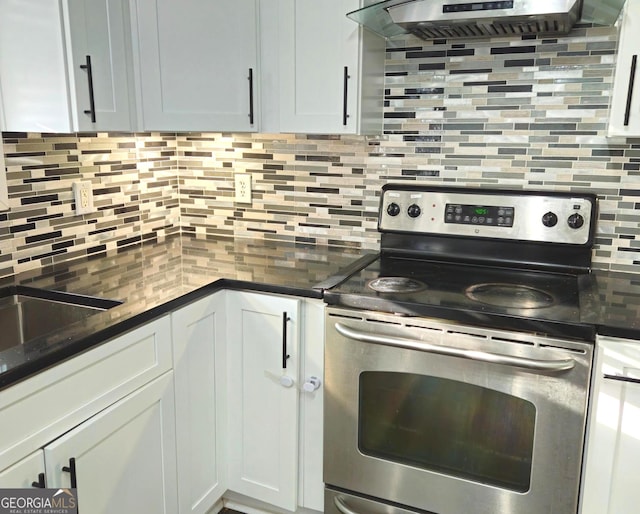 kitchen featuring backsplash, dark stone counters, white cabinets, stainless steel electric range oven, and extractor fan