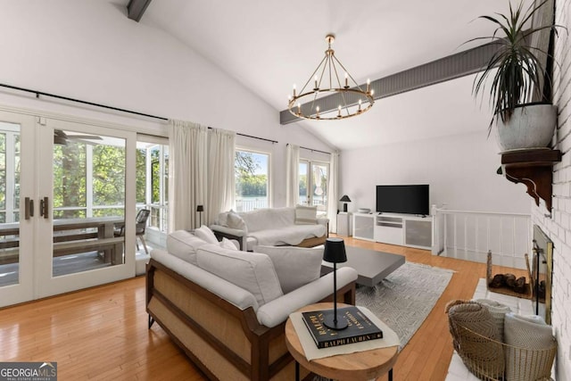 living room with french doors, light wood-type flooring, lofted ceiling with beams, and an inviting chandelier