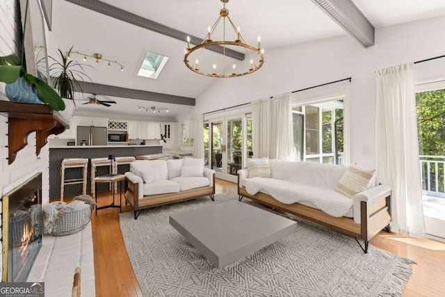 living room with ceiling fan with notable chandelier, plenty of natural light, a fireplace, and light hardwood / wood-style flooring