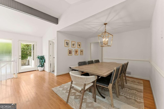 dining space featuring lofted ceiling with beams, light hardwood / wood-style flooring, and an inviting chandelier