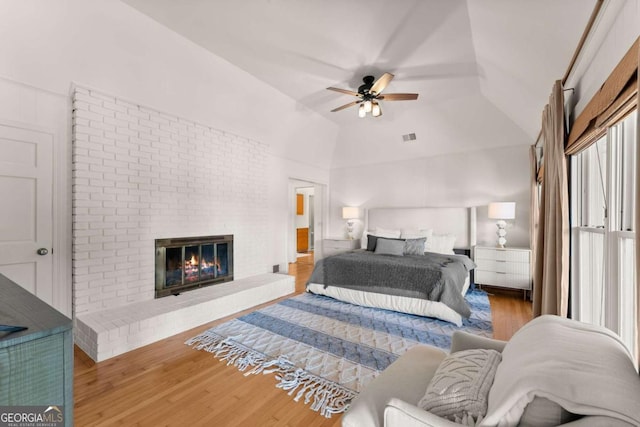 bedroom with ceiling fan, a fireplace, hardwood / wood-style floors, and lofted ceiling