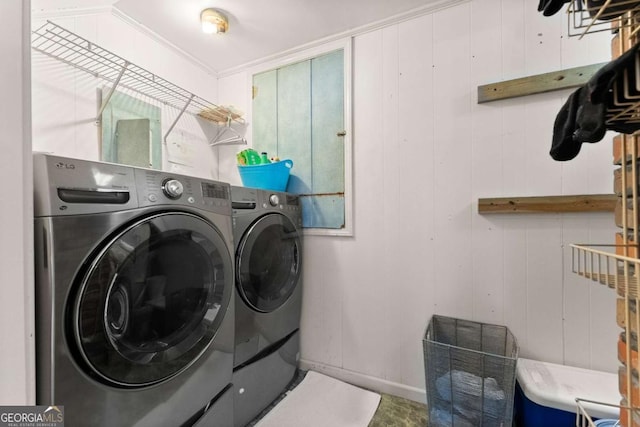 washroom featuring wooden walls, ornamental molding, and washing machine and clothes dryer