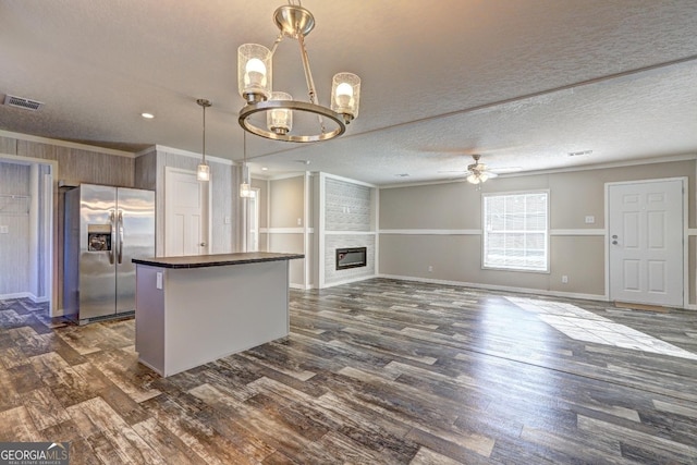 kitchen featuring ceiling fan with notable chandelier, pendant lighting, a large fireplace, stainless steel fridge, and ornamental molding