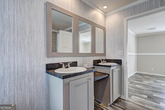 bathroom featuring vanity, hardwood / wood-style floors, a textured ceiling, and crown molding