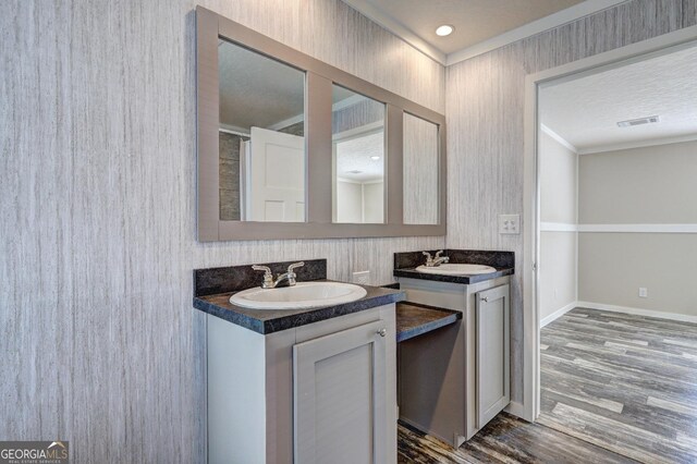 bathroom with hardwood / wood-style flooring, a tub to relax in, vanity, and ornamental molding