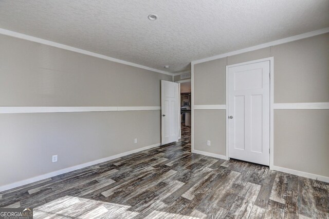 empty room featuring dark wood-type flooring, a textured ceiling, and ornamental molding