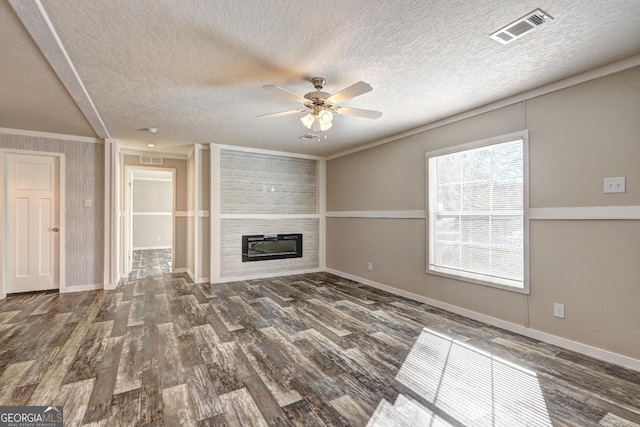 unfurnished living room featuring a textured ceiling, a large fireplace, ornamental molding, dark wood-type flooring, and ceiling fan