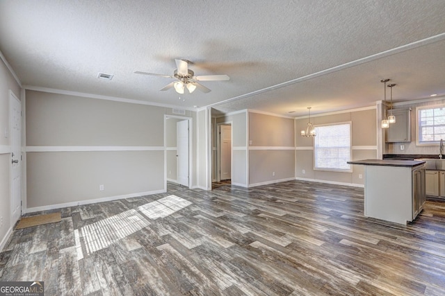 unfurnished living room featuring a textured ceiling, a large fireplace, ornamental molding, dark wood-type flooring, and ceiling fan