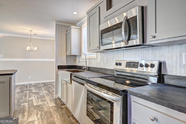 kitchen featuring dark hardwood / wood-style flooring, stainless steel appliances, sink, gray cabinets, and a notable chandelier